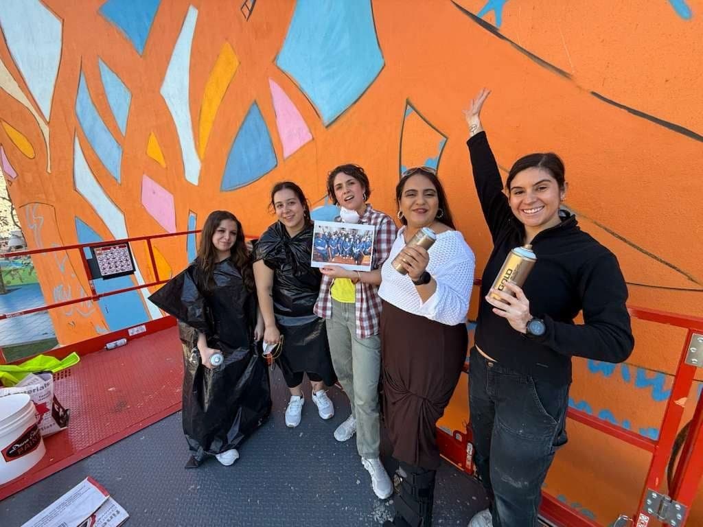 Mural crew celebrating in front of a finished orange mural